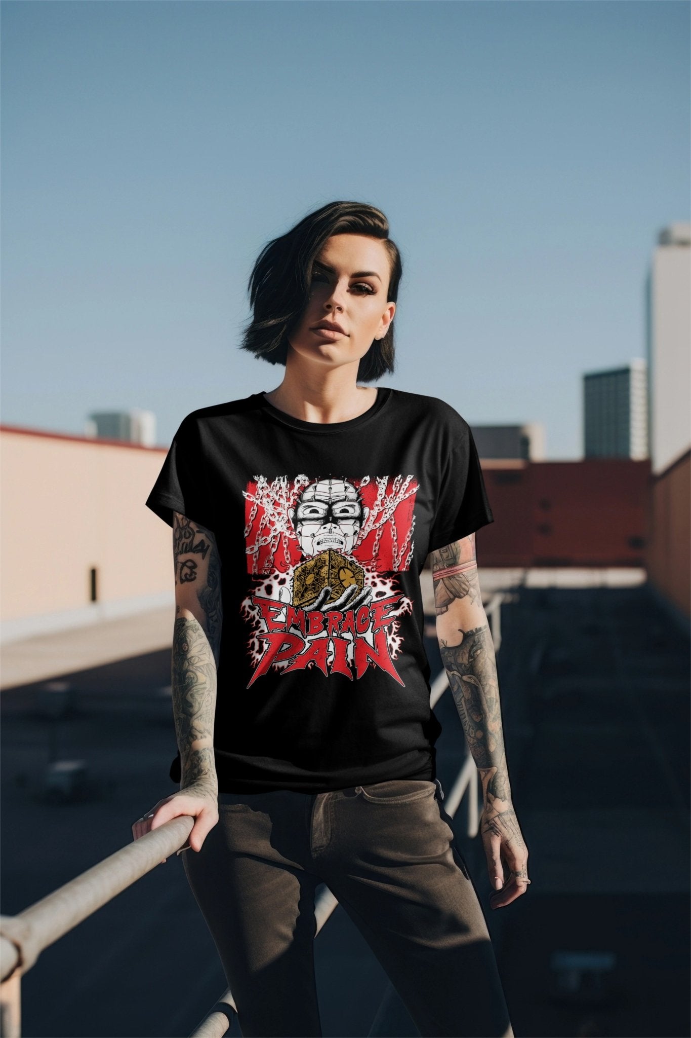 A goth or punk woman wearing a black t-shirt with an illustration by Glow Bat Alternative Fashion of Pinhead from the Hellraiser horror movie franchise holding the lament configuration above the words "embrace pain"