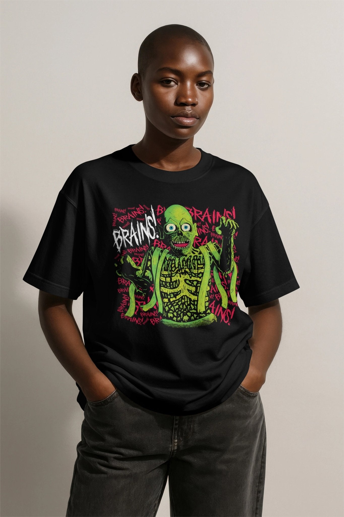 A woman wearing a black t-shirt featuring the Return of the Zombie design Glow Bat Alternative fashion. The design is an original illustration of the Tarman Zombie from Return of the Living Dead in green with the word "Brains" scrawled behind it in pink.